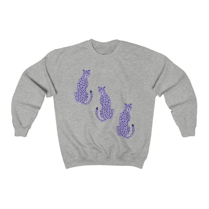 May include: A gray sweatshirt with a purple cheetah print design. Three cheetahs are sitting in a row on the front of the sweatshirt.