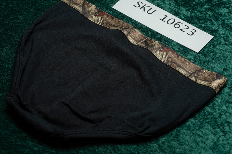 May include: Black headwear with a camouflage pattern along the top edge. The tag in the image reads "SKU 10623". The headwear appears to be made of a soft, flexible material.