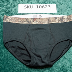 May include: Black briefs with a camouflage waistband. The briefs are made of a soft material and have a classic design. The waistband features a brown and green camouflage pattern. SKU 10623 is printed on a white label.