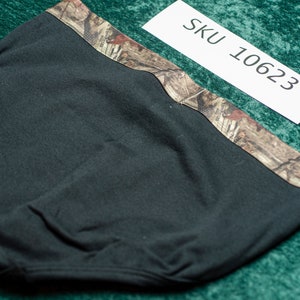 May include: Black head covering with a camouflage pattern along the top edge. The head covering is made of a soft, dark fabric. A white tag with "SKU 10623" is visible.
