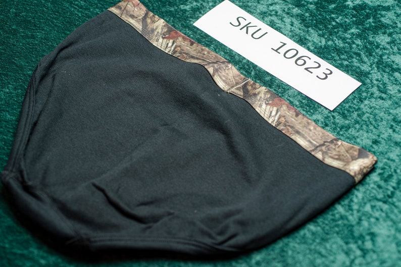 May include: Black head covering with a camouflage pattern along the top edge. The head covering is made of a soft, dark fabric. A white tag with "SKU 10623" is visible.