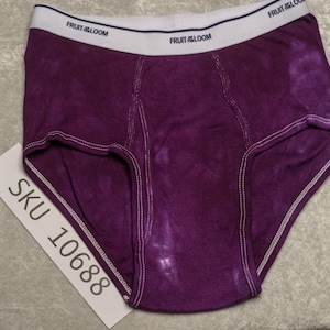 Peut inclure: Slip de couleur violette tie-dye avec une ceinture blanche portant le logo "FRUIT OF THE LOOM". Le slip présente des coutures blanches et une étiquette avec "SKU 10688".