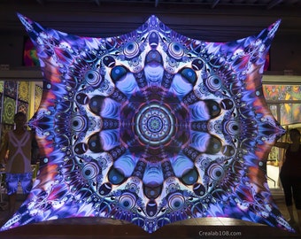 Op de afbeelding: Een groot, kleurrijk, geometrisch patroon van een stoffen luifel met een blauw, paars en oranje kleurenschema. De stof is strak gespannen en lijkt van achteren te worden verlicht.