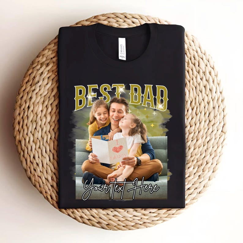 May include: Black t-shirt with a gold "Best Dad" graphic and a photo of a father reading a card to his two daughters. The text "Your text here" is below the photo.