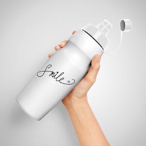 Puede incluir: Botella de agua blanca con tapa negra y correa negra. La botella tiene la palabra "Smile" escrita en ella en cursiva negra.