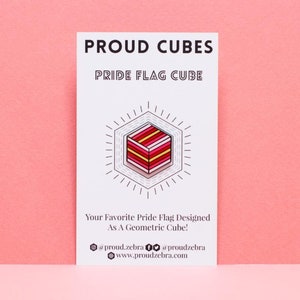 May include: A white card with the text "PROUD CUBES" and "PRIDE FLAG CUBE" in black text. A geometric cube design in red, pink, yellow, and white is shown on the card. The text "Your Favorite Pride Flag Designed As A Geometric Cube!" is below the cube. The text "proud zebra" and "www.proudzebra.com" is at the bottom of the card.