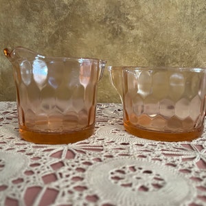 Puede incluir: Un juego de dos jarras de crema y azucareros de vidrio rosa con un diseño texturizado en forma de panal.