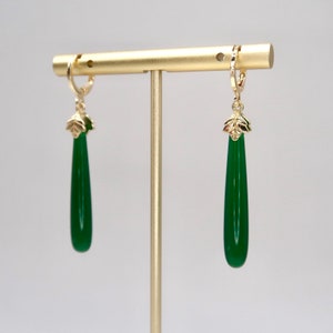 May include: A pair of green gemstone drop earrings with gold leaf accents and gold hoops.