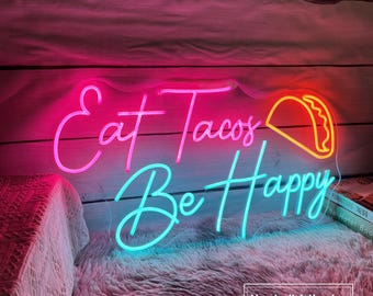 May include: Neon sign with pink and blue lights that reads "Eat Tacos Be Happy" with a pink and yellow taco graphic.