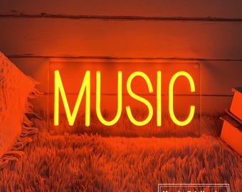 May include: A neon sign with the word "MUSIC" in yellow letters on a clear acrylic background. The sign is illuminated and casting a warm orange glow.
