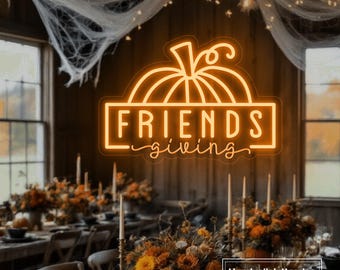 May include: An orange neon sign featuring a pumpkin outline above a rectangular border containing the text FRIENDS in block letters and the word giving in cursive script, centered above a dining table with floral arrangements and candles.