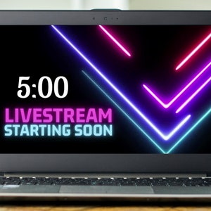 May include: A laptop screen displaying a countdown timer with the text "5:00 LIVE STREAM STARTING SOON" in pink and blue neon text against a black background with neon pink and blue lines.