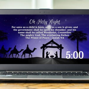 May include: A laptop screen shows a Christmas image with the text "Oh Holy Night" and a Bible verse. Silhouettes of the nativity scene and three wise men on camels are visible. The time 5:00 is displayed in white.
