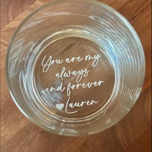 May include: A clear glass tumbler with etched text that reads "You are my always and forever Lauren" with a heart symbol. The glass is round and sits on a wooden surface.