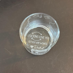 May include: A clear glass votive candle holder with etched text. The text reads "I FUCKING LOVE YOU (EITHER WAY WORKS) ❤️ Rachel". The candle holder is round and sits on a dark surface.