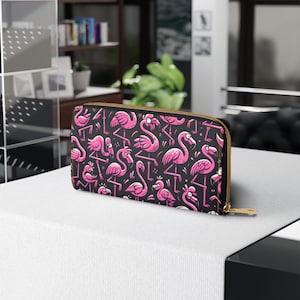 Peut inclure: Portefeuille noir avec un motif répété de flamants roses. Le portefeuille a une fermeture éclair dorée et repose sur une surface blanche. Les flamants roses sont dans diverses poses.