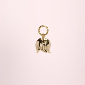 Op de afbeelding: Een goudkleurige bedel in de vorm van een lelietje-van-dalenbloem. De bedel heeft een kleine lus aan de bovenkant om aan een ketting of armband te bevestigen. De bloem heeft een gedetailleerd, driedimensionaal ontwerp.