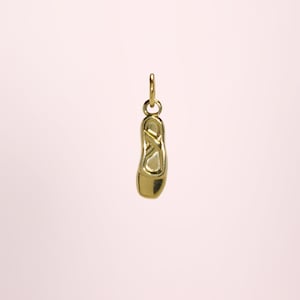 Peut inclure: Un charm doré en forme de chausson de danse. Le charm possède une boucle en haut pour l'attacher à un collier ou un bracelet. Le charm de chausson de danse est un bijou délicat et élégant.