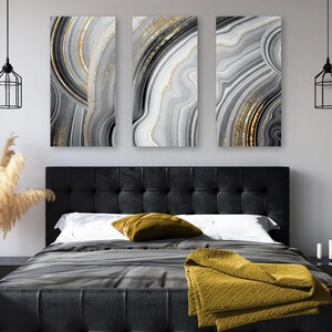 May include: A set of three vertical wall art panels featuring abstract agate-inspired patterns in shades of black, white, and gray with metallic gold accents. The designs consist of flowing, concentric lines and layers resembling natural stone.
