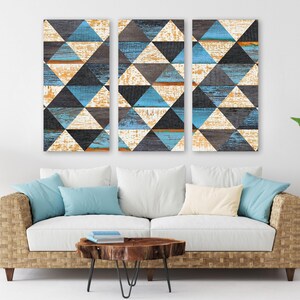 May include: A three-panel wall art set featuring a geometric pattern of triangles in shades of blue, black, and distressed white. The design displays a weathered wood grain texture across all three vertical rectangular panels arranged side by side.