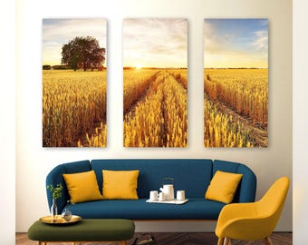 May include: A triptych wall art set featuring a golden wheat field at sunset with a single tree on the left panel and a path leading toward the horizon in the center panel. The scene is rendered in warm yellow, orange, and blue sky tones.