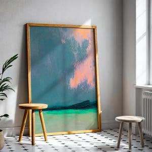 K&ouml;nnte beinhalten: Ein gro&szlig;es, gerahmtes abstraktes Gem&auml;lde mit T&uuml;rkis-, Rosa- und Gr&uuml;nt&ouml;nen. Das Kunstwerk lehnt an einer Wand, neben einem kleinen Holzschemel. Eine Topfpflanze und ein weiterer Hocker befinden sich ebenfalls im Raum.