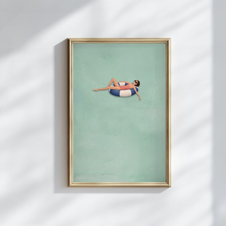 Pu&ograve; includere: Una stampa artistica da parete incorniciata che presenta un'illustrazione minimalista di una persona con costume da bagno rosso e occhiali da sole, che galleggia su un salvagente circolare a righe blu e bianche su sfondo verde chiaro.