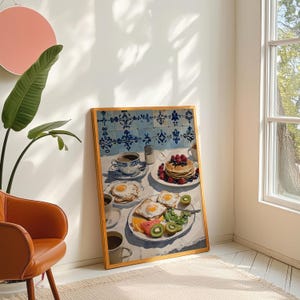 Puede incluir: Una impresi&oacute;n enmarcada de una escena de desayuno. La imagen presenta una mesa con caf&eacute;, panqueques con bayas y huevos fritos con fruta. El fondo tiene azulejos estampados azules y blancos.