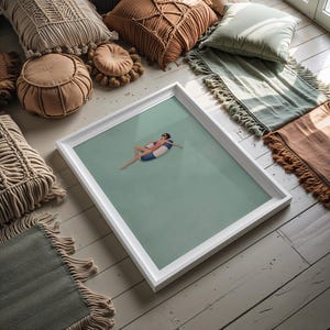 Pu&ograve; includere: Una stampa artistica incorniciata che ritrae una persona in costume da bagno rosa e occhiali da sole che galleggia su un salvagente a righe blu e bianche in acqua calma color verde chiaro. L'opera &egrave; presentata in una semplice cornice bianca.