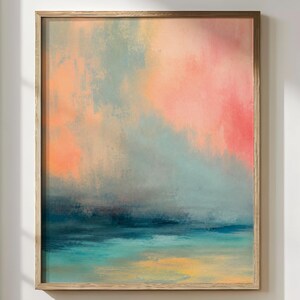 Könnte beinhalten: Abstrakter Kunstdruck in einem Holzrahmen. Das Kunstwerk zeigt eine Mischung aus Farben, darunter Rosa, Orange, Türkis und Blau, wodurch ein weicher, strukturierter Effekt entsteht. Das Gemälde erinnert an eine Landschaft oder Seelandschaft.