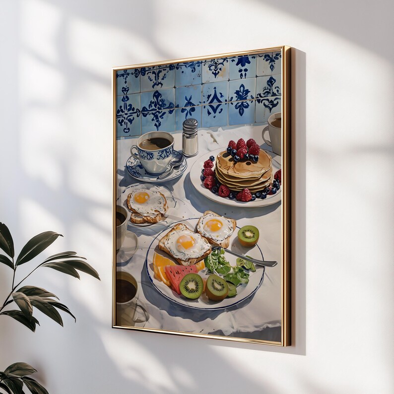Puede incluir: Pintura enmarcada de una escena de desayuno. La pintura representa una mesa con panqueques, huevos, fruta y caf&eacute;. El fondo presenta azulejos azules y blancos estampados. La obra de arte est&aacute; enmarcada en un marco dorado.