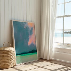 K&ouml;nnte beinhalten: Ein abstrakter Kunstdruck in einem wei&szlig;en Rahmen. Das Kunstwerk zeigt eine Mischung aus T&uuml;rkis-, Gr&uuml;n- und Pfirsicht&ouml;nen, die eine Landschaft oder Seelandschaft hervorrufen. Die gerahmte Kunst lehnt an einer wei&szlig;en Wand, mit einem Weidenkorb und einem Fenster mit Strandblick.
