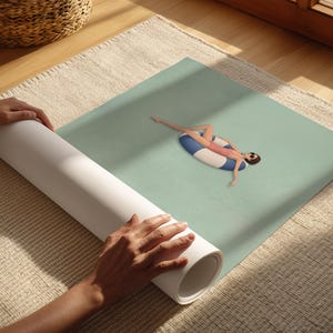 Pu&ograve; includere: Una stampa su tela arrotolata che presenta un'illustrazione digitale di una figura con costume da bagno rosa e occhiali da sole, che galleggia su un salvagente a righe blu e bianche in acqua calma color verde chiaro. L'opera &egrave; su una superficie ruvida.
