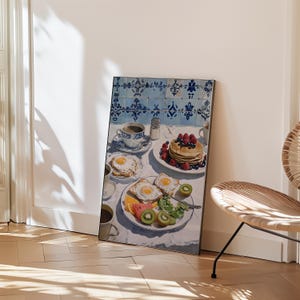 Puede incluir: Impresi&oacute;n enmarcada de una escena de desayuno con panqueques con bayas, huevos fritos, tostadas, fruta y caf&eacute;. La mesa est&aacute; puesta con un mantel blanco y vajilla con dise&ntilde;os azules y blancos. El fondo presenta azulejos azules y blancos.