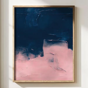 Könnte beinhalten: Abstrakter Kunstdruck in einem Holzrahmen. Das Kunstwerk zeigt ein strukturiertes, geschichtetes Design mit einem dunkelblauen oberen Bereich und einem zartrosa unteren Bereich. Das Gemälde wird vor einer weißen Wand ausgestellt.