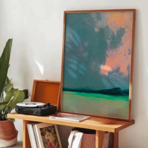 K&ouml;nnte beinhalten: Abstrakter Kunstdruck in einem Holzrahmen mit T&uuml;rkis-, Orange- und Gr&uuml;nt&ouml;nen. Ein schwarzer Plattenspieler mit silberner Schallplatte steht auf einem Holztisch, zusammen mit einer Schallplattenh&uuml;lle und einem geflochtenen Korb.