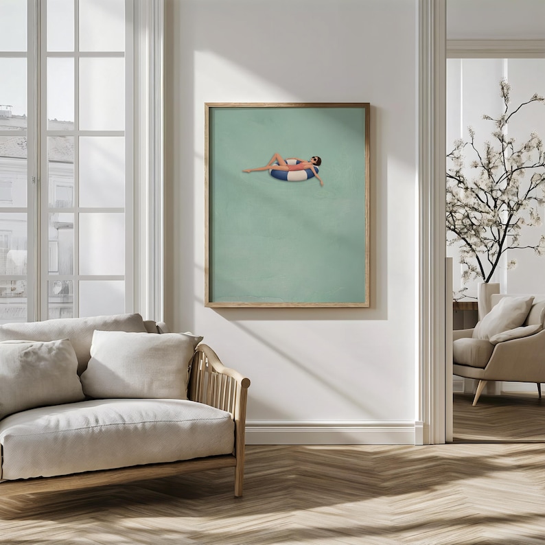 Pu&ograve; includere: Una stampa artistica incorniciata che presenta un'illustrazione minimalista di una persona sdraiata su un salvagente a righe blu e bianche in una piscina verde chiaro a tinta unita. L'opera &egrave; esposta in una sottile cornice di legno.