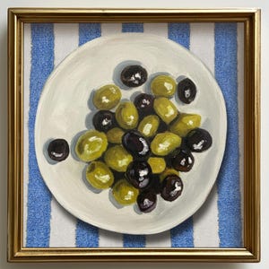 May include: A framed painting depicting a white plate with green and black olives. The plate rests on a blue and white striped cloth. The artwork is presented in a gold frame.