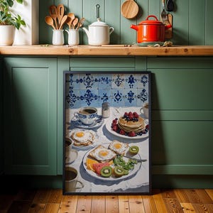 Puede incluir: Una impresi&oacute;n enmarcada de una escena de desayuno con panqueques, huevos, fruta y caf&eacute;. La obra de arte est&aacute; ambientada sobre un fondo de azulejos azules y blancos. La cocina tiene gabinetes verdes y encimeras de madera.