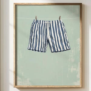 Blue and white striped swim shorts wall art print featuring vintage style men’s swim trunks hanging on a line against a soft coastal green textured background. Retro beachwear inspired artwork with cool ocean tones and a relaxed, sun-faded aesthetic, perfect for coastal bathroom decor, Airbnb styling, poolside interiors, and beach house wall art. Designed to pair with matching striped swimsuit artwork for a cohesive summer gallery wall.