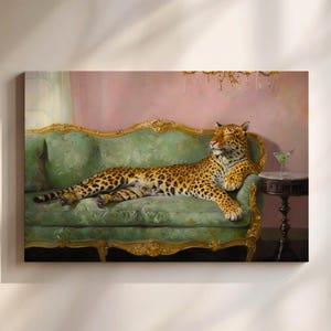 Op de afbeelding: Een canvas print toont een luipaard dat ontspannen op een groene fluwelen bank met gouden details ligt. Een klein tafeltje houdt een martini vast. De achtergrond heeft een roze muur en sierlijke gouden accenten, wat een luxueuze scène creëert.
