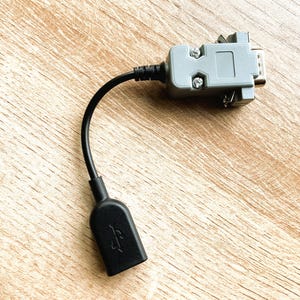 以下が含まれることがあります： 片側にグレーの接続端子、もう片側に黒いUSB接続端子を持つ黒いケーブル