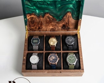 May include: A wooden watch display case with a green resin lid and six watches. The box is made of dark wood and has a hinged lid. The watches are in various styles, including digital and analog, with metal, leather, and fabric straps.