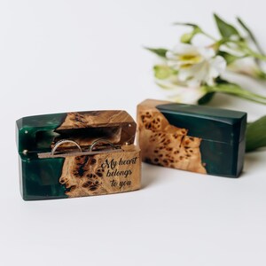 May include: Two wooden ring boxes with a dark green resin accent. One box is open, displaying two rings, and the text "My heart belongs to you." The other box is closed. The boxes have a natural wood grain pattern.