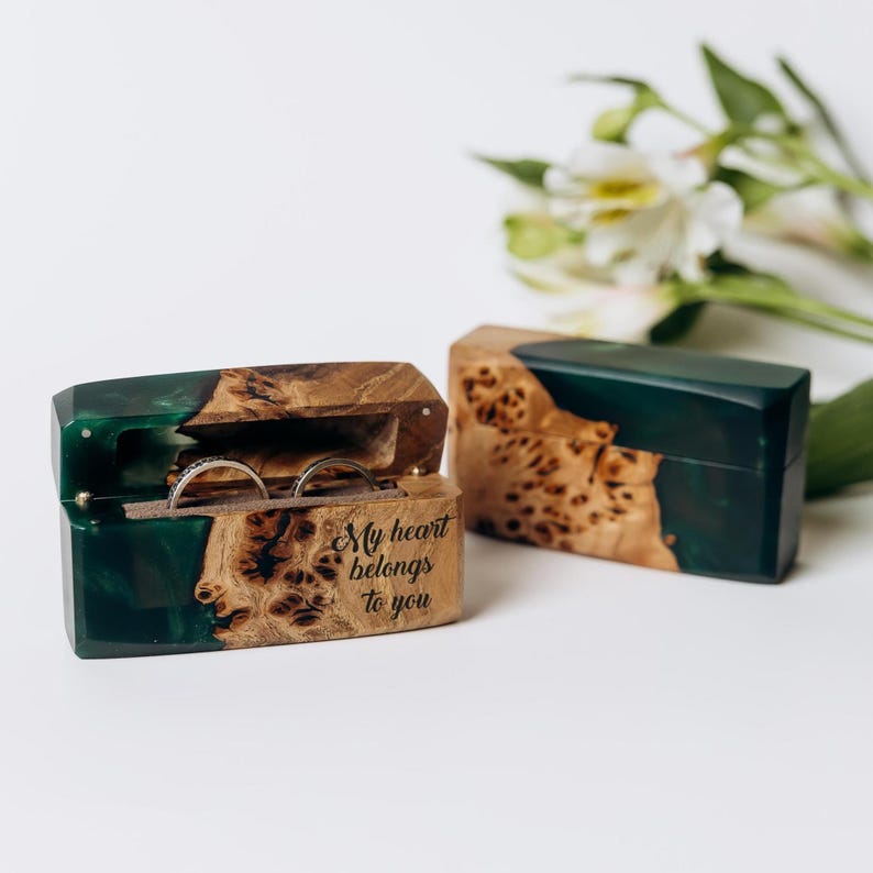 May include: Two wooden ring boxes with a dark green resin accent. One box is open, displaying two rings, and the text "My heart belongs to you." The other box is closed. The boxes have a natural wood grain pattern.