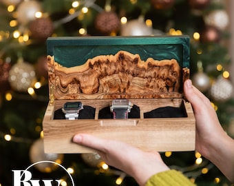 May include: A rectangular wooden watch box with three interior compartments and black velvet cushions. The lid features a natural wood grain edge combined with a smooth, dark green resin inlay. Two wristwatches are stored inside the box.