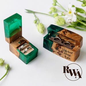 Op de afbeelding: Twee houten ringendoosjes met groene harsaccenten. Eén doosje is open en toont twee ringen. Het andere doosje is ook open en toont twee ringen en de inscriptie "My heart belongs to you."