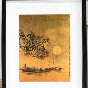 May include: Framed art print depicting a serene moonlit scene with a boat on the water. The artwork features a full moon, a tree branch, and a boat with a person. The print is in a black frame with a white mat.