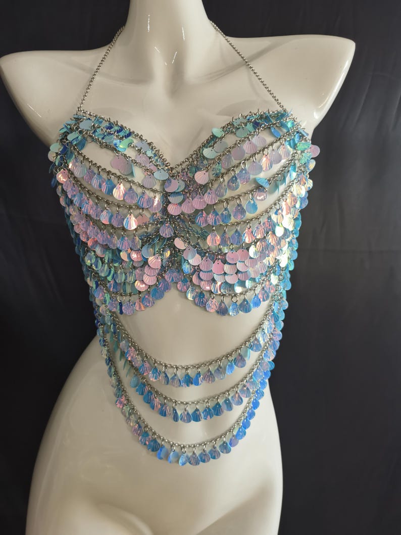 May include: A halter-style top constructed from silver-toned metal chains and iridescent, teardrop-shaped sequins. The garment features multiple draped layers of shimmering blue and pink scales that create a textured, reflective surface across the chest.