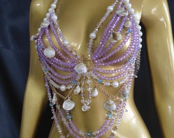 May include: A halter-style body chain top constructed from multiple strands of lavender and clear beads, interspersed with white pearls and small natural seashells. The design features a draped, layered aesthetic with gold-toned metal chains.